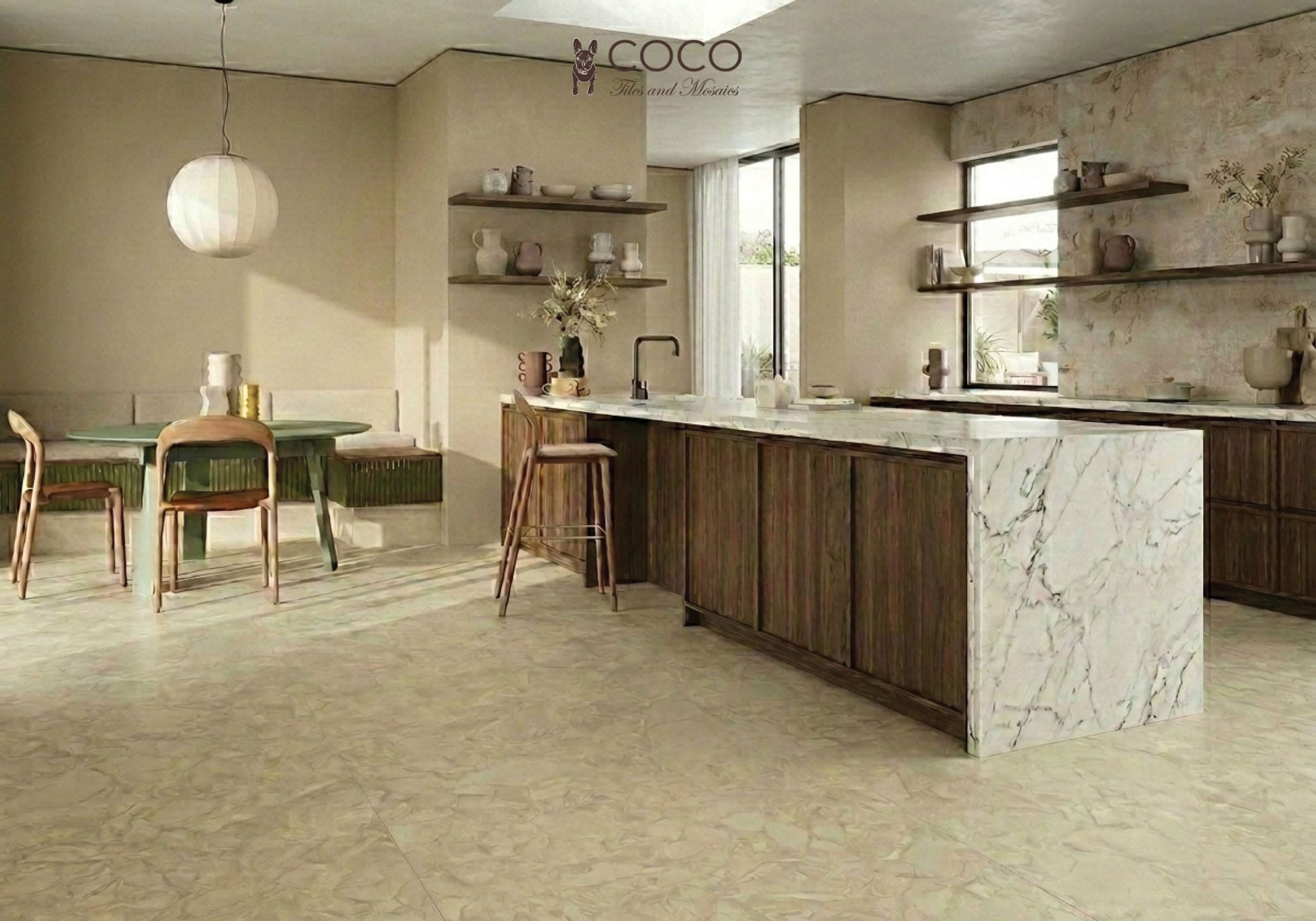A warm, organic-modern kitchen featuring the Trattoria tile look. The floor is laid with Fragmenta Series Cappuccino 600x600mm creamy beige terrazzo-look tiles. The kitchen wall behind open timber shelving features Babylon Series Villa B 500x1200mm ceramic tiles, displaying a subtle botanical relief pattern with an aged plaster effect. The space includes a marble waterfall island, dark walnut cabinetry, a round green dining table, and a paper lantern pendant light.