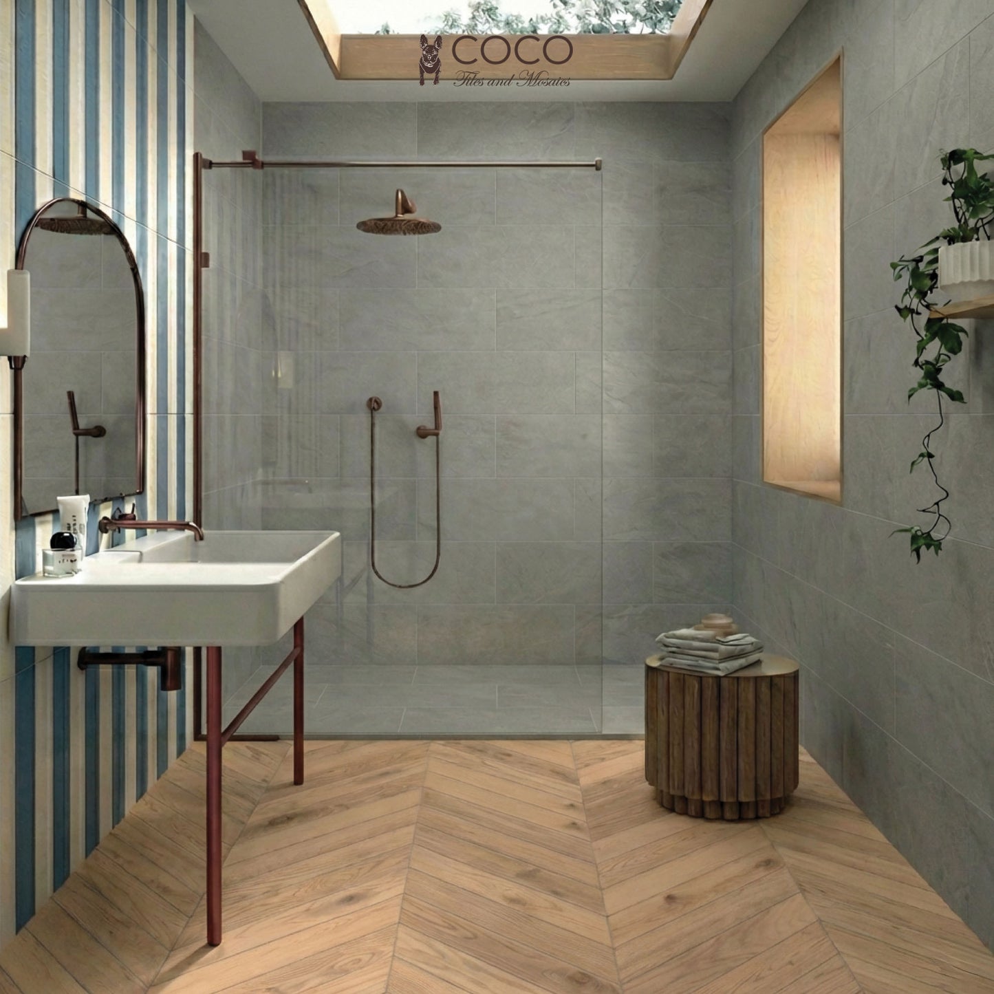 A modern coastal bathroom featuring a blue and white vertical striped feature wall, a chevron wood-look porcelain tile floor, and light grey main walls. The room includes a white vessel sink on a copper-legged vanity and a glass shower screen.
